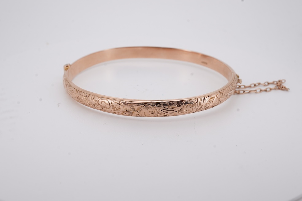 A George V part engraved 9ct gold hollow hinged bangle, Birmingham, 1911, interior diameter 57mm, 5.5 grams. Condition - poor